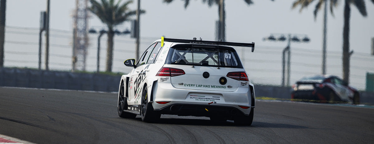The number 67 Dutch Brothers Racing Golf, seen from behind on track at Yas Marina Circuit with palm trees along the barrier.