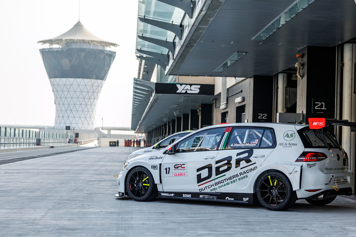 The number 17 Dutch Brothers Racing Golf in the pit lane at Yas Marina Circuit, the Yas Hotel tower rising behind the garages.