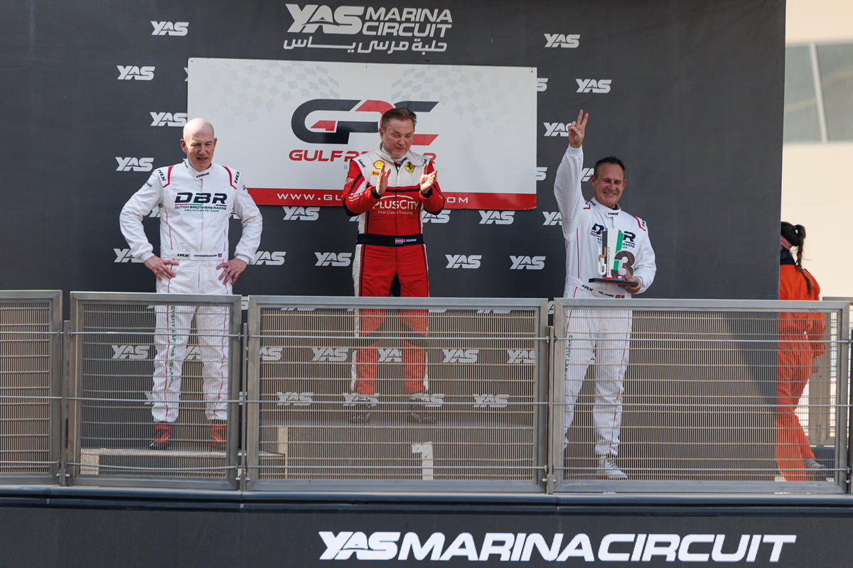 The podium at Yas Marina Circuit in front of the Gulf ProCar backdrop, a Dutch Brothers Racing driver raising his arm to the crowd.