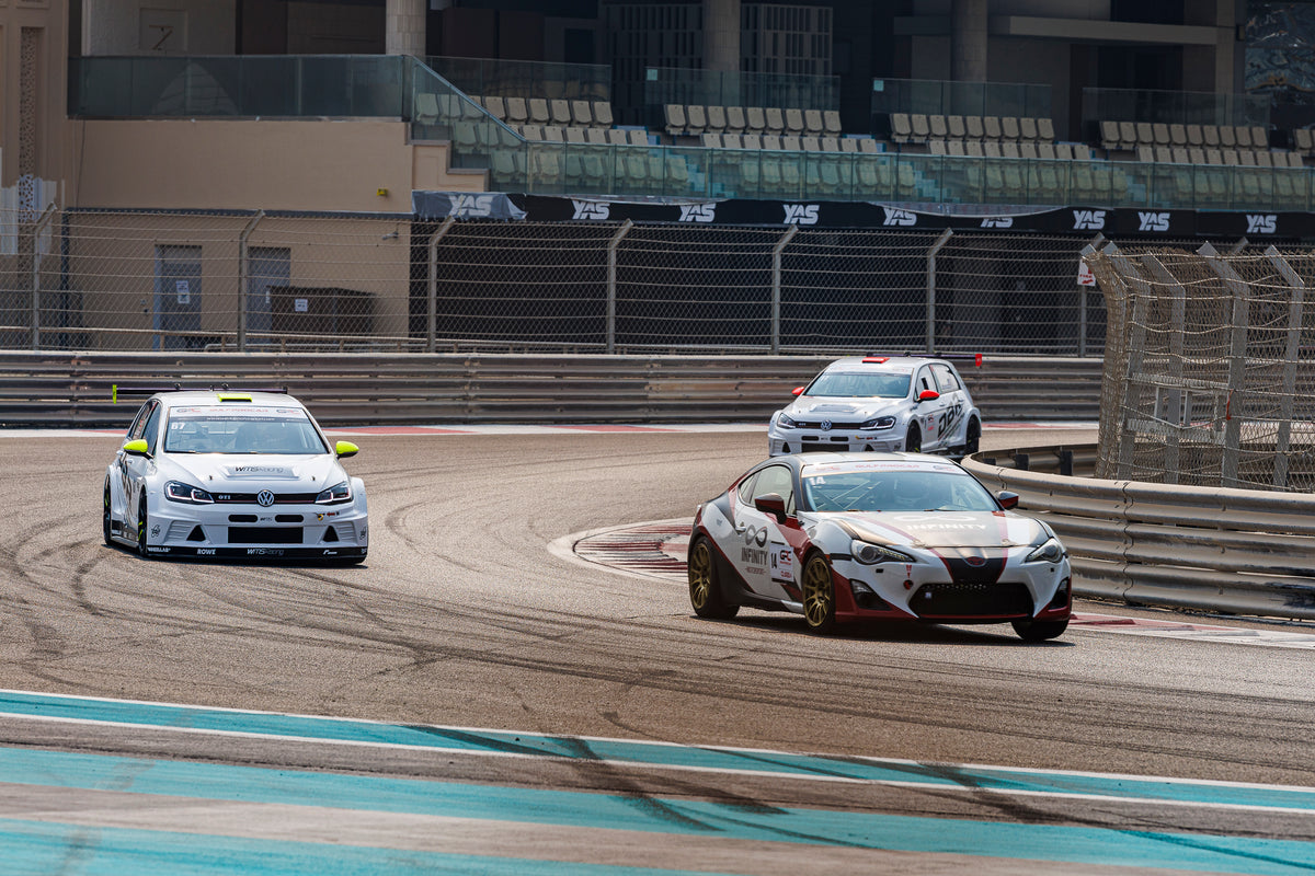 The Dutch Brothers Racing Golf running side by side with two rival cars through a corner at Yas Marina Circuit.