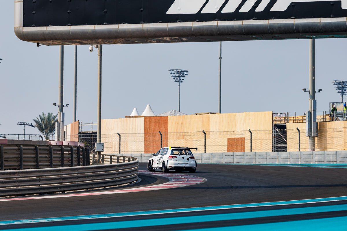 The Dutch Brothers Racing Golf alone on a distant part of the Yas Marina circuit, grandstand hoardings and floodlights behind.