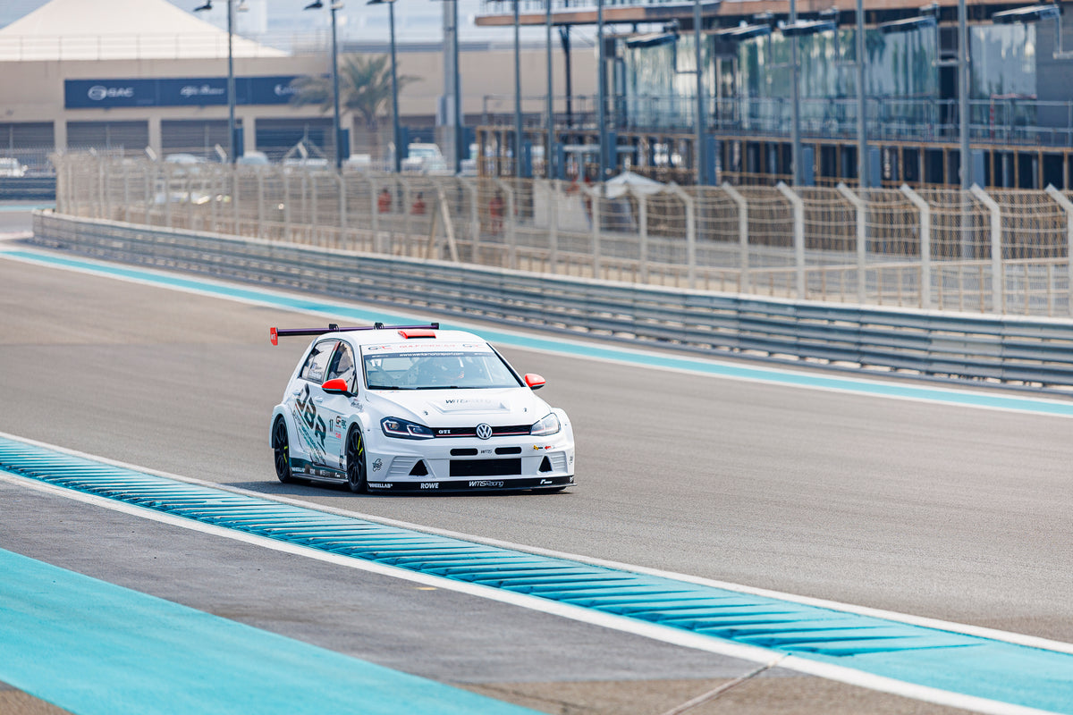 The Dutch Brothers Racing Golf at speed between the blue kerbs at Yas Marina Circuit, catch fencing behind.