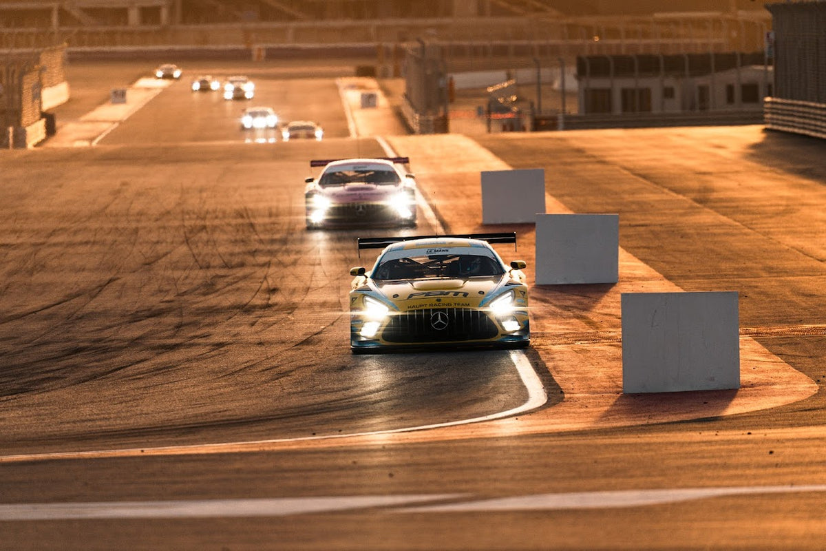 GT race cars competing at Dubai Autodrome at sunset.