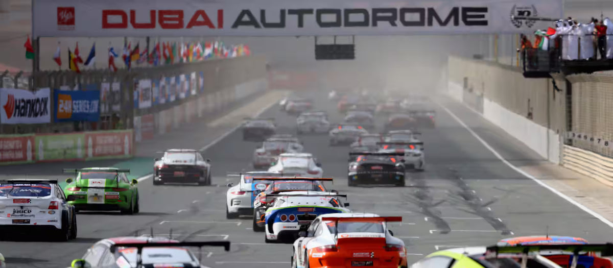 A field of race cars accelerating down the main straight at Dubai Autodrome.