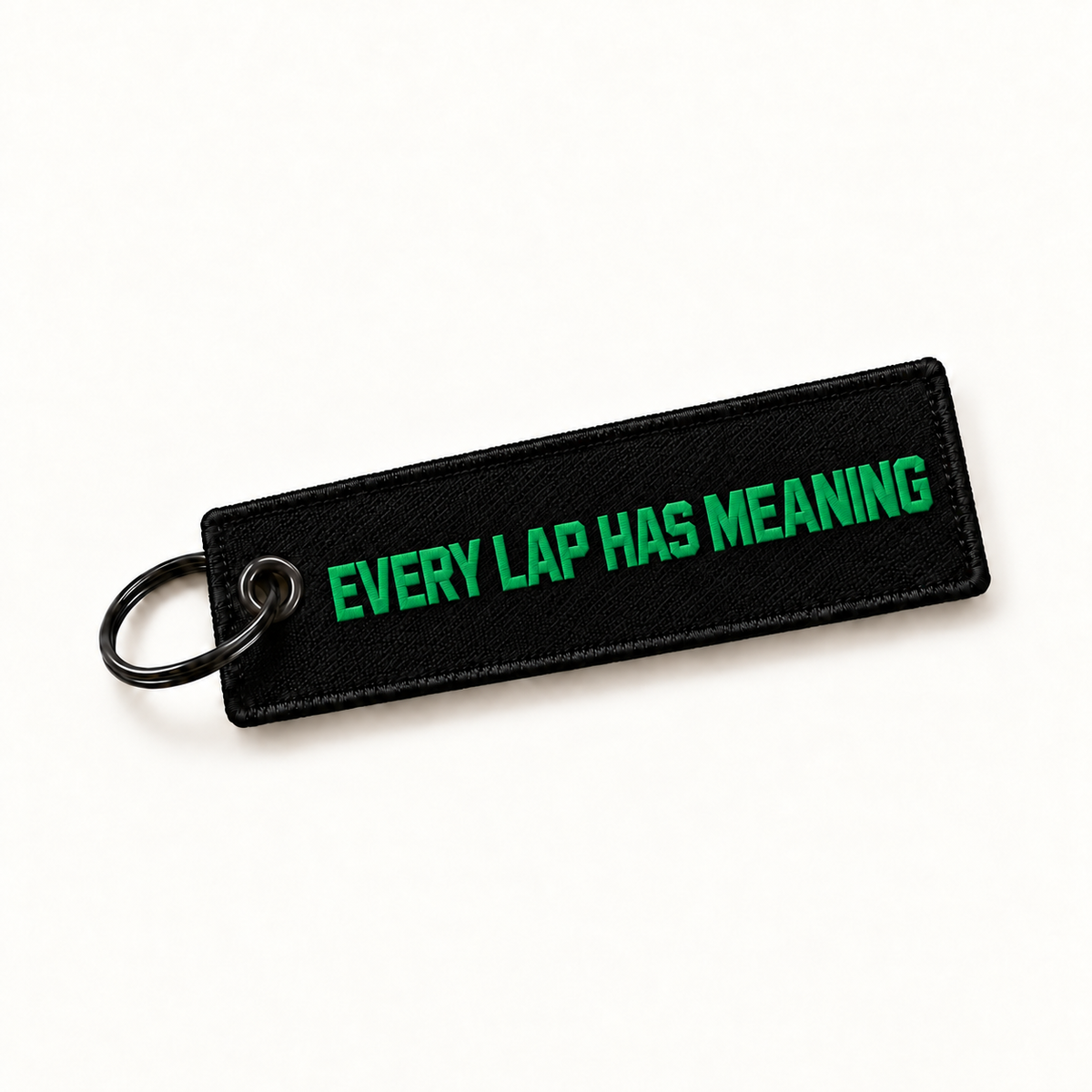 Reverse of the Dutch Brothers Racing keyring, with Every Lap Has Meaning embroidered in green on the black woven tag.